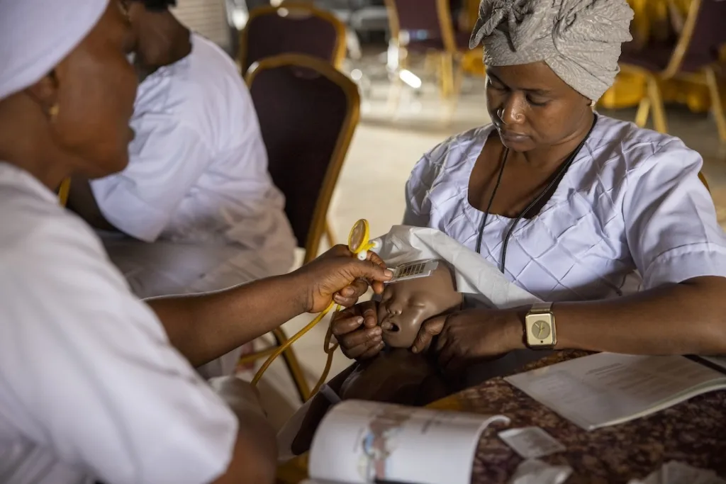 Two nurses learning how to care for newborn in a training