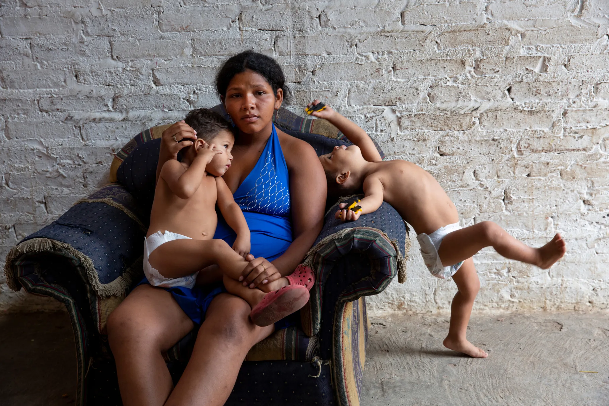 Mother sitting on armchair with her two young children