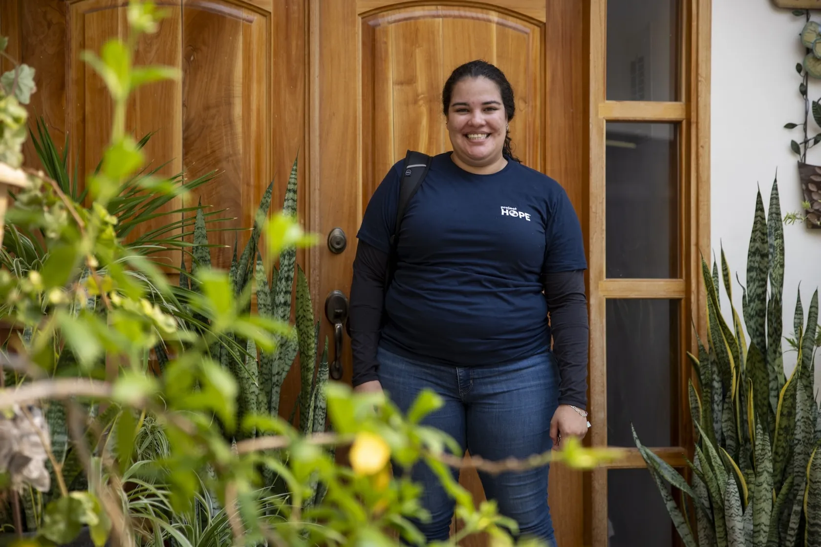 woman in Project HOPE shirt outside in front of wooden door