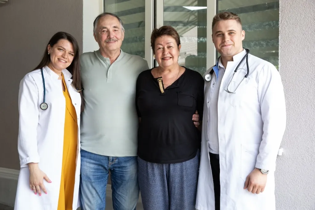 group of people in medical outfits posing with two patients